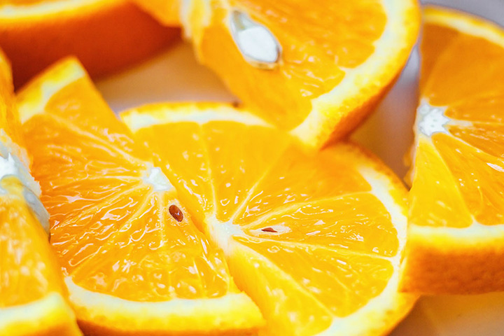 Natural Pharmaceuticals „CalciumControl™“ Ryškios oranžinės apelsinų skiltelės su sultinga tekstūra ir matomais sėklomis arti.